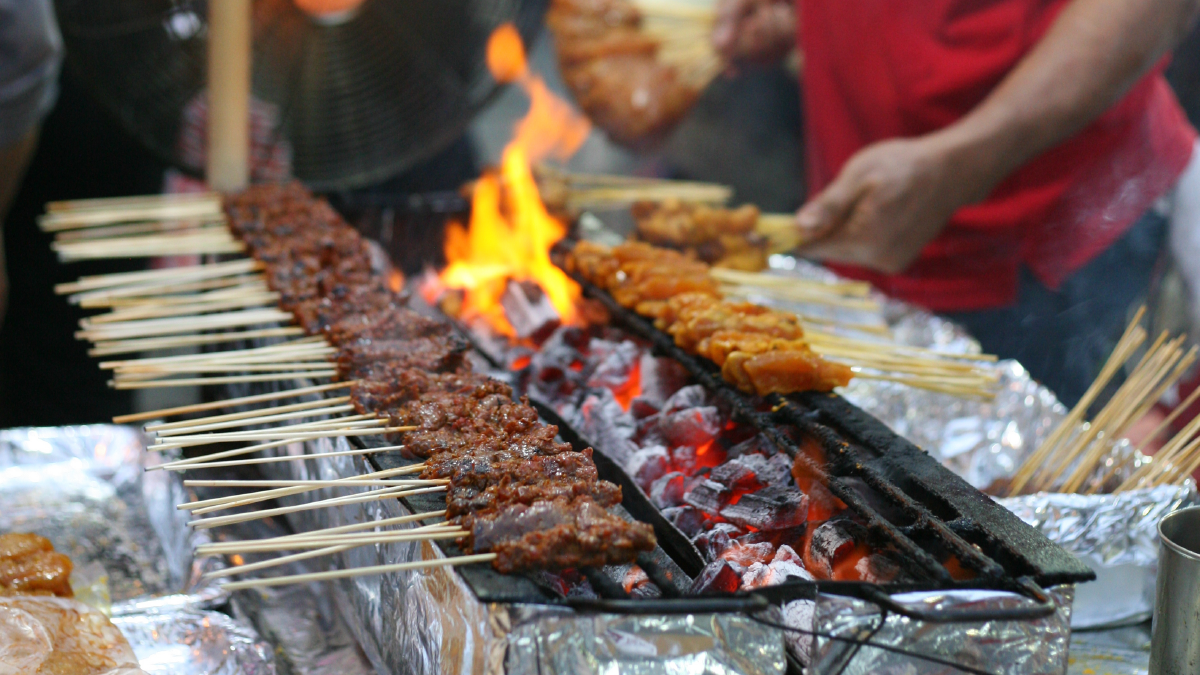 Satay: Meat grilled on a skewer and served with a spiced sauce that typically contains peanuts, ketupat (rice cakes), onions and cucumbers.